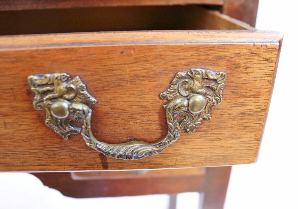 A George III mahogany lowboy featuring three drawers with brass handles, a central shaped apron, and four square legs. View VI