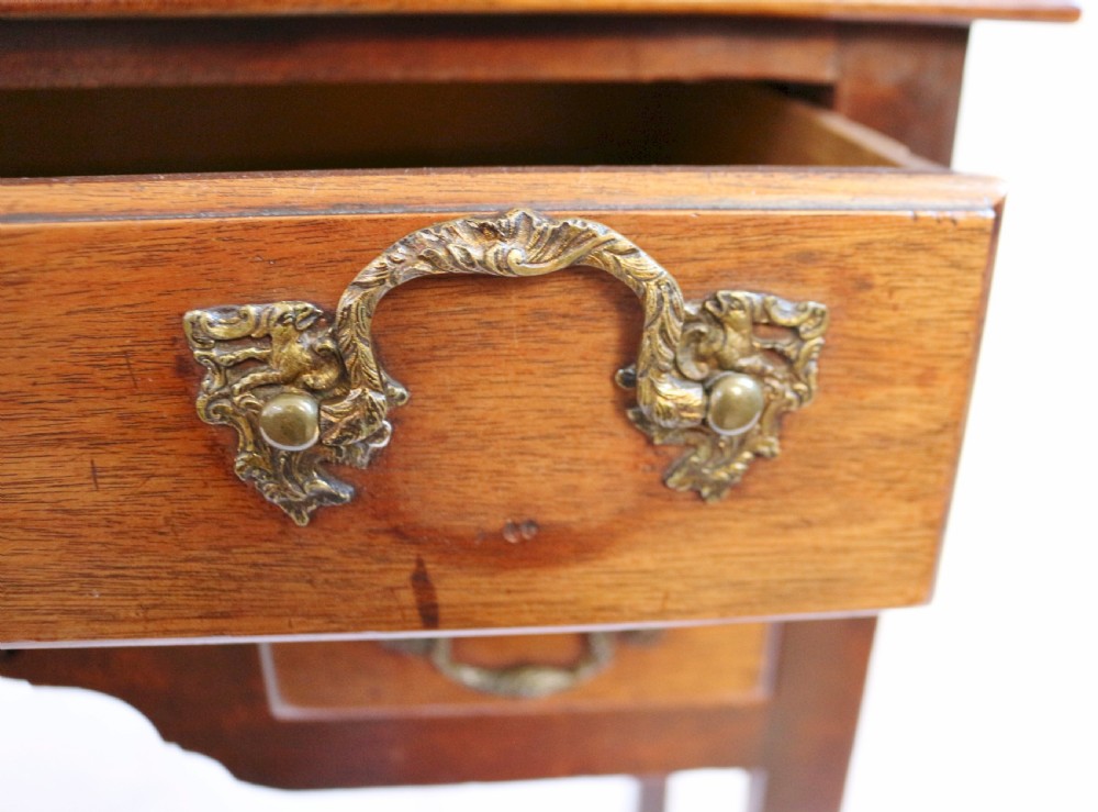 A George III mahogany lowboy featuring three drawers with brass handles, a central shaped apron, and four square legs. View VII