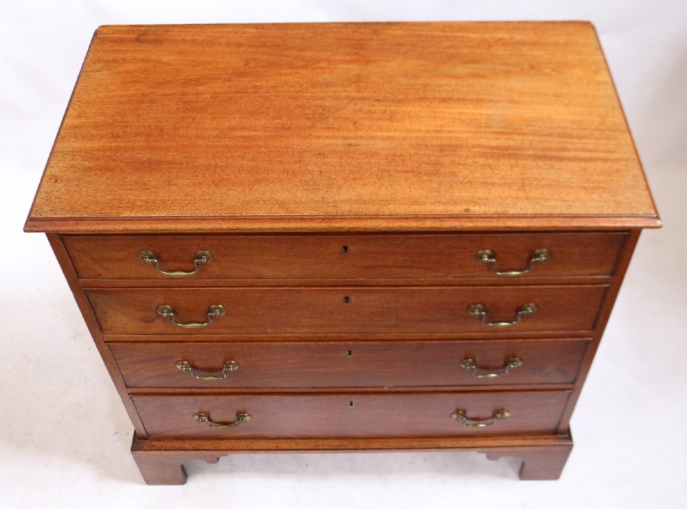 A George III mahogany four-drawer chest featuring brass swan-neck handles, keyhole escutcheons, and bracket feet. View V