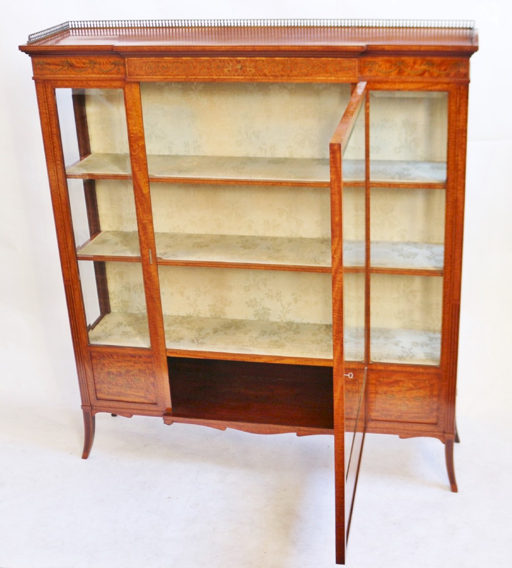 An antique satinwood display cabinet featuring a single central glazed door, fabric-lined interior shelves, floral marquetry inlay, and slightly splayed legs. View II