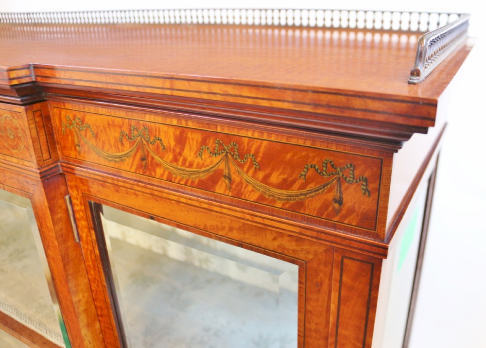 An antique satinwood display cabinet featuring a single central glazed door, fabric-lined interior shelves, floral marquetry inlay, and slightly splayed legs. View IV