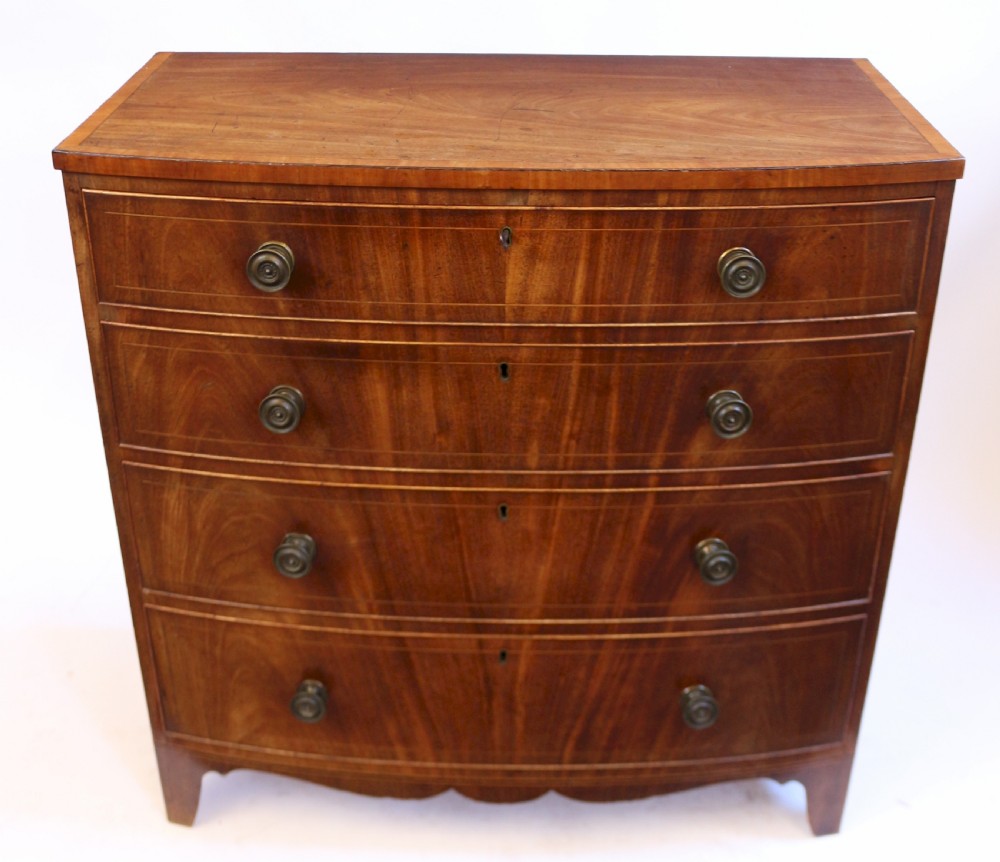 A George III mahogany bowfront chest of drawers featuring four graduated drawers with turned knobs and boxwood string inlay.