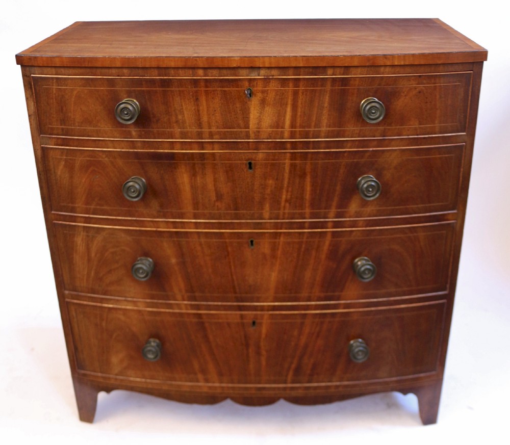 A George III mahogany bowfront chest of drawers featuring four graduated drawers with turned knobs and boxwood string inlay. View II