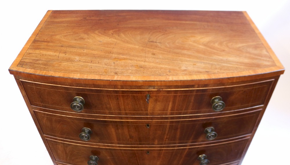 A George III mahogany bowfront chest of drawers featuring four graduated drawers with turned knobs and boxwood string inlay. View III
