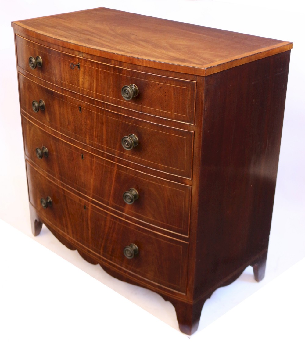 A George III mahogany bowfront chest of drawers featuring four graduated drawers with turned knobs and boxwood string inlay. View V