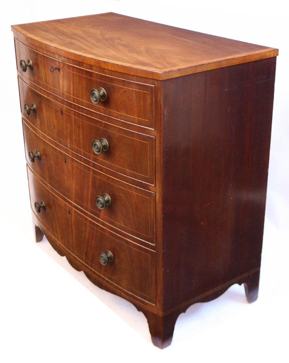 A George III mahogany bowfront chest of drawers featuring four graduated drawers with turned knobs and boxwood string inlay. View VI