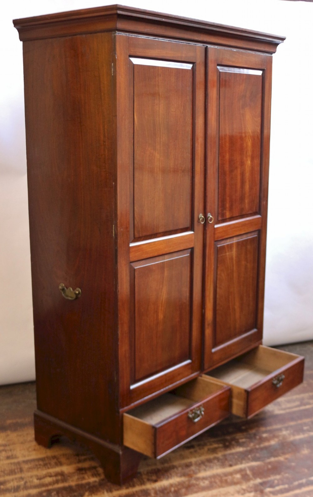 A George III mahogany two-door wardrobe featuring fielded panel doors, two base drawers with brass handles, a moulded cornice, and bracket feet. View III
