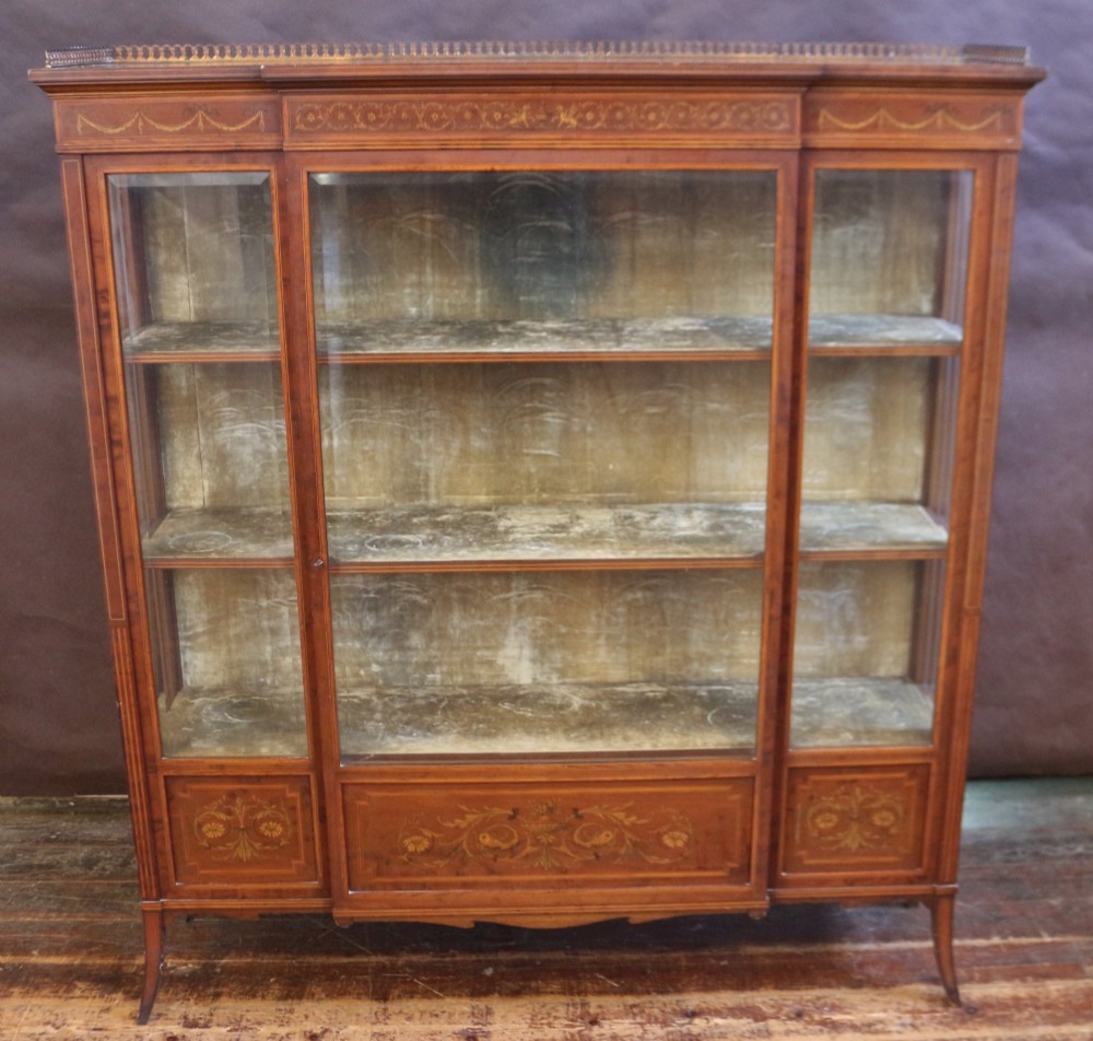An Edwardian mahogany display cabinet featuring satinwood floral marquetry inlays, glazed doors and side panels, and square tapered legs.