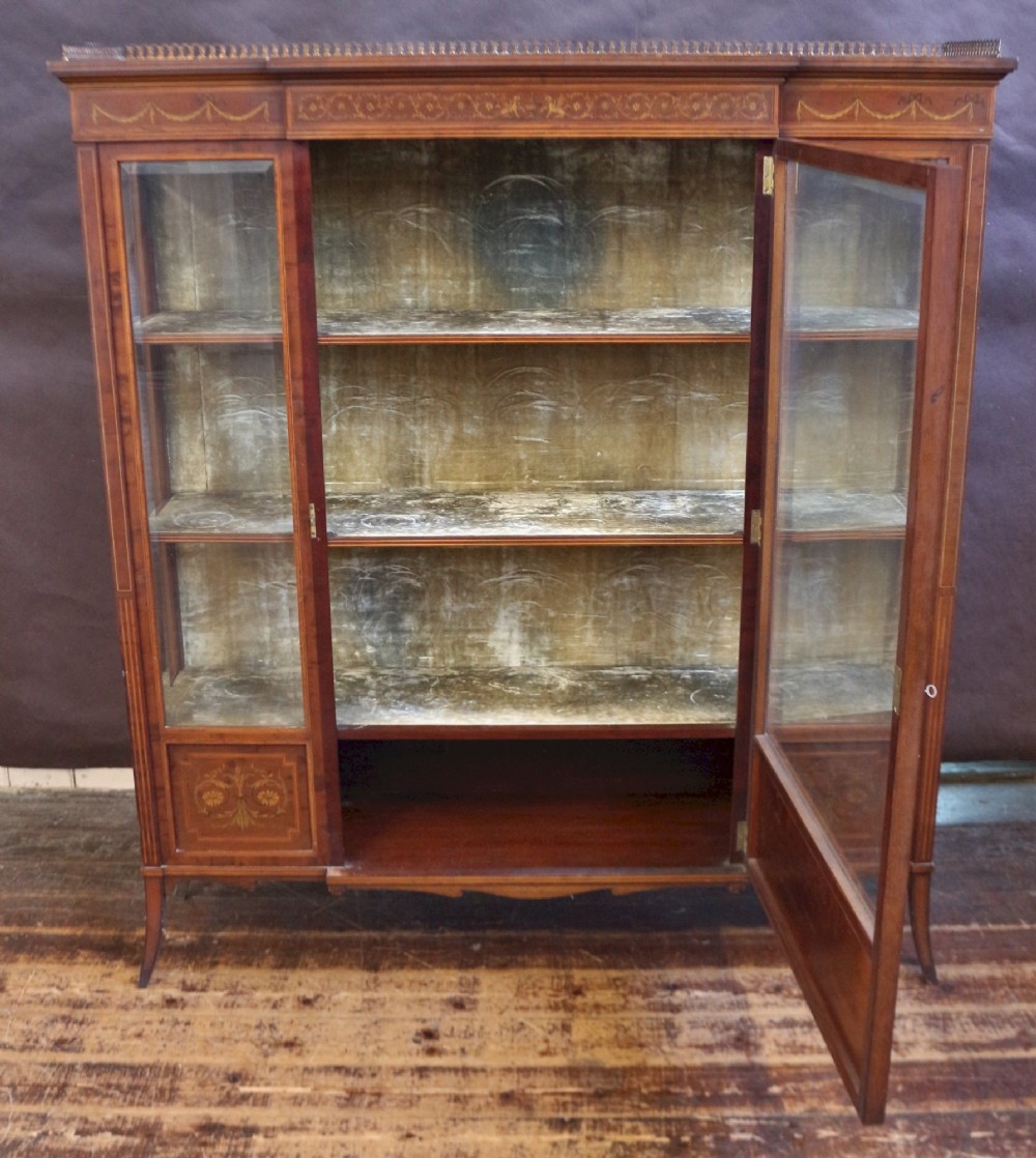 An Edwardian mahogany display cabinet featuring satinwood floral marquetry inlays, glazed doors and side panels, and square tapered legs. View II