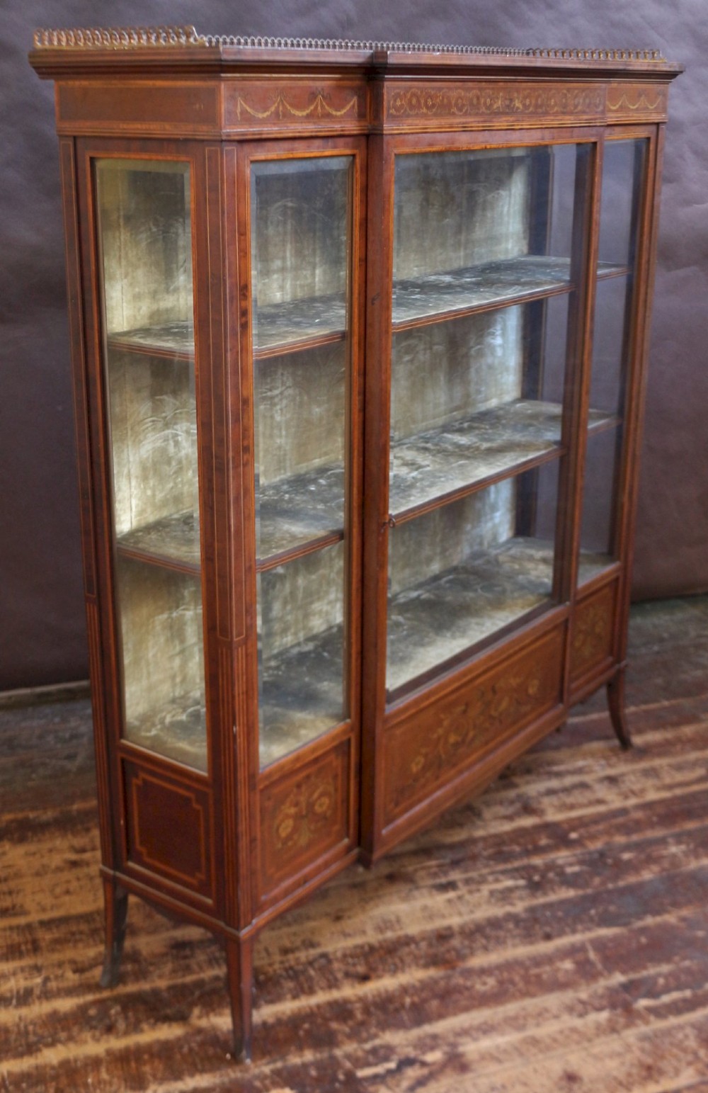 An Edwardian mahogany display cabinet featuring satinwood floral marquetry inlays, glazed doors and side panels, and square tapered legs. View III