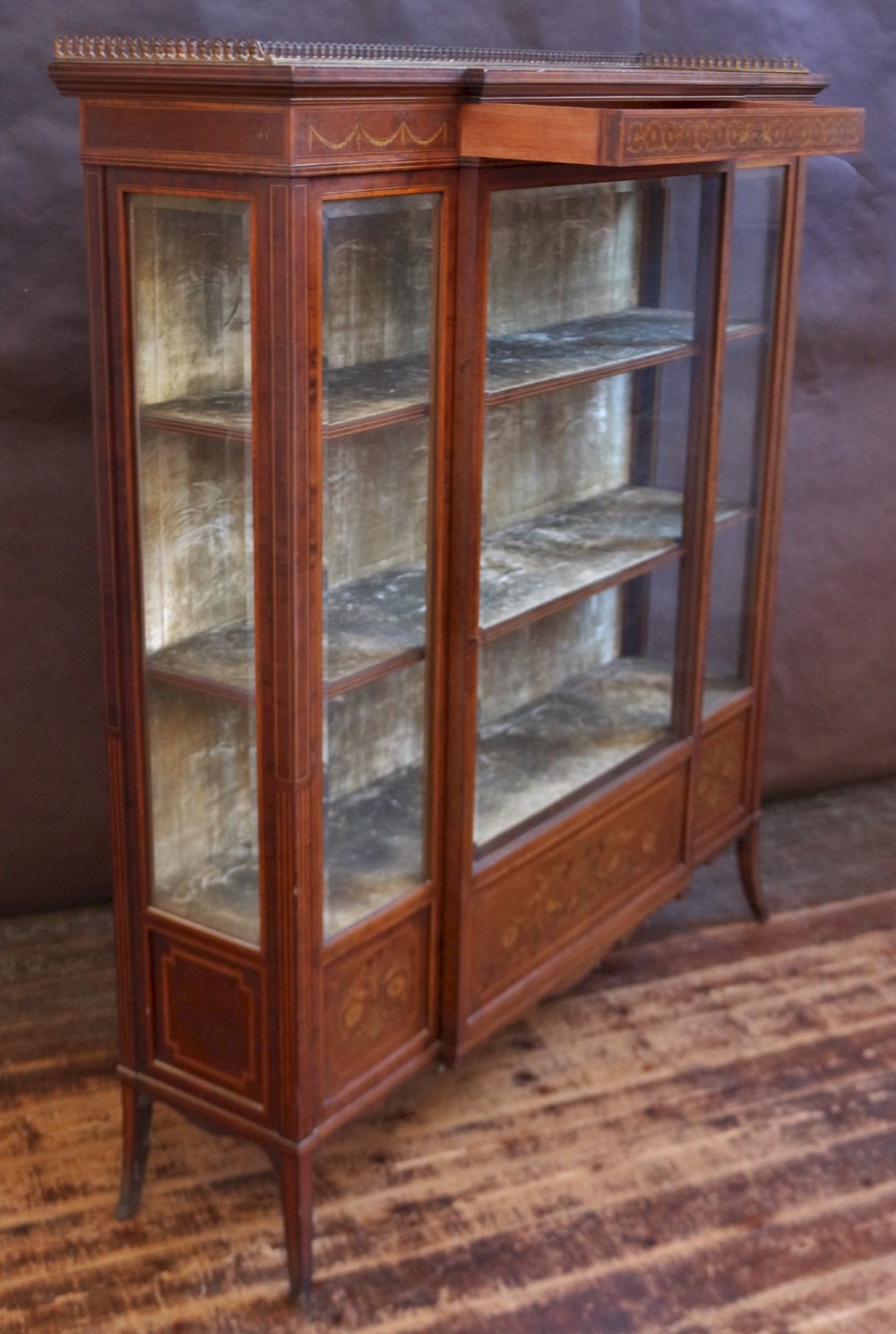 An Edwardian mahogany display cabinet featuring satinwood floral marquetry inlays, glazed doors and side panels, and square tapered legs. View IV