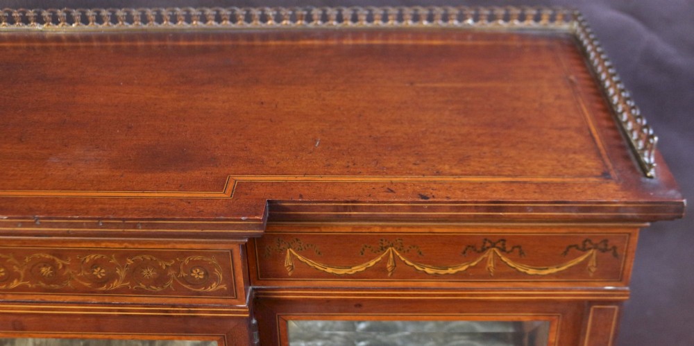 An Edwardian mahogany display cabinet featuring satinwood floral marquetry inlays, glazed doors and side panels, and square tapered legs. View VII