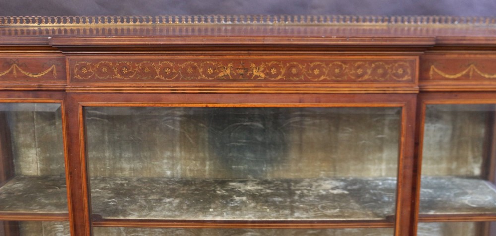 An Edwardian mahogany display cabinet featuring satinwood floral marquetry inlays, glazed doors and side panels, and square tapered legs. View VIII