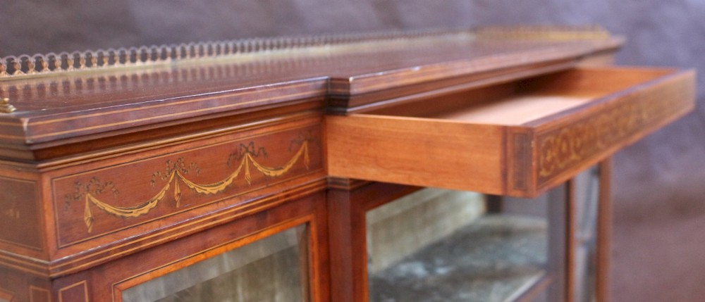 An Edwardian mahogany display cabinet featuring satinwood floral marquetry inlays, glazed doors and side panels, and square tapered legs. View X