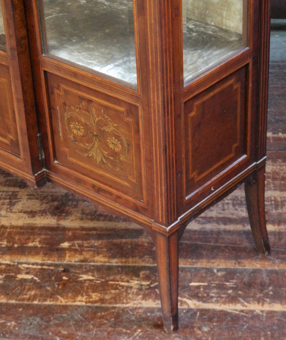 An Edwardian mahogany display cabinet featuring satinwood floral marquetry inlays, glazed doors and side panels, and square tapered legs. View XI