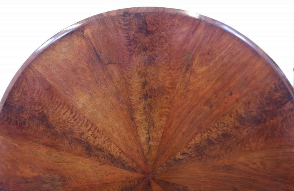A William IV circular mahogany centre table featuring a sunburst veneered top, a central faceted column, and a triform plinth base supported by carved lion paw feet. View V