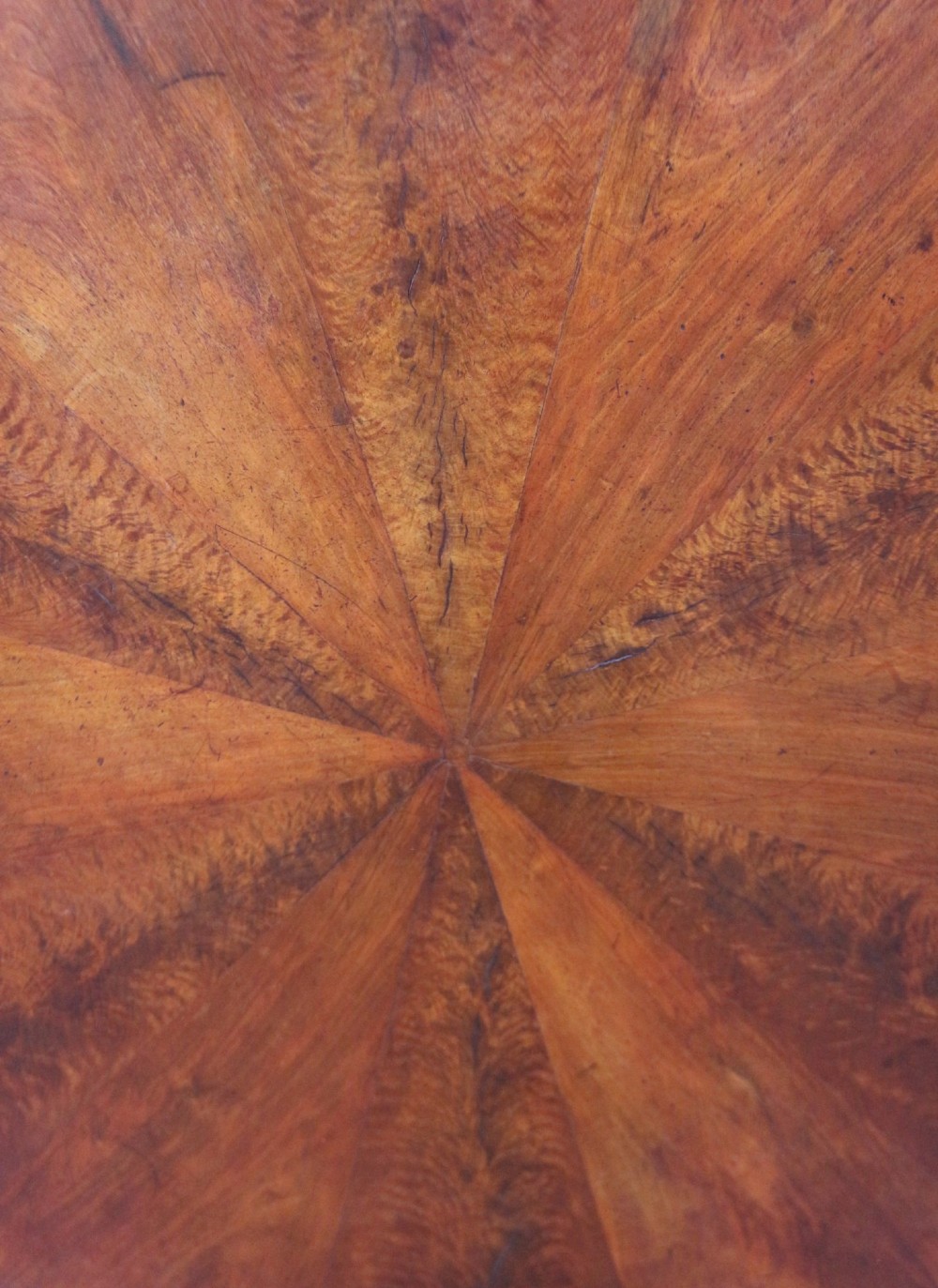 A William IV circular mahogany centre table featuring a sunburst veneered top, a central faceted column, and a triform plinth base supported by carved lion paw feet. View VI