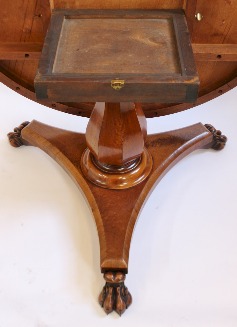 A William IV circular mahogany centre table featuring a sunburst veneered top, a central faceted column, and a triform plinth base supported by carved lion paw feet. View VII
