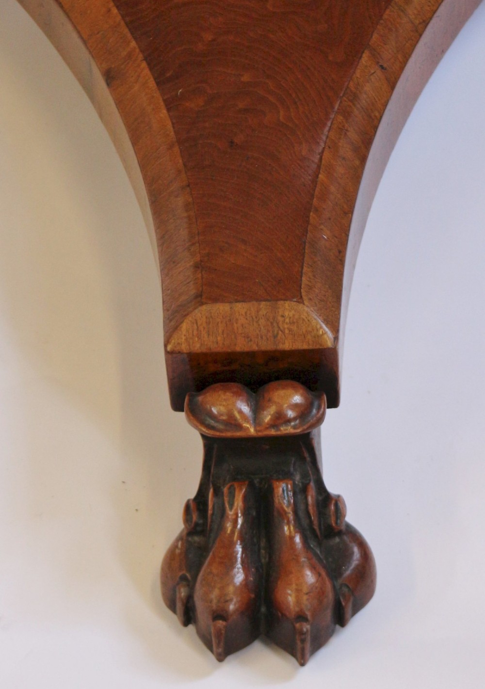 A William IV circular mahogany centre table featuring a sunburst veneered top, a central faceted column, and a triform plinth base supported by carved lion paw feet. View VIII