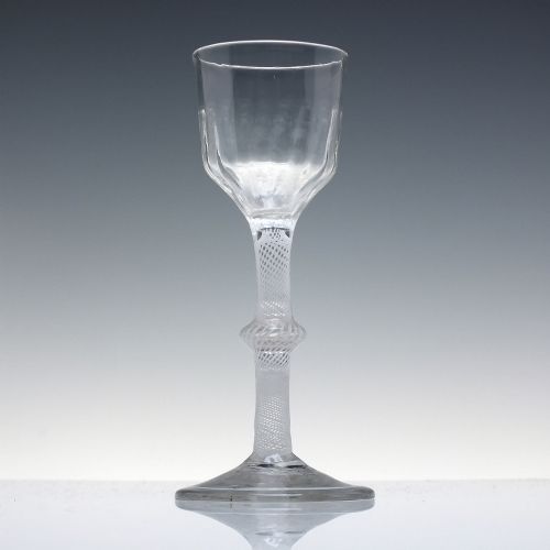 fig 1. An 18th-century clear glass wine glass featuring a multi-spiral opaque white twist stem with a central knop and a round foot.