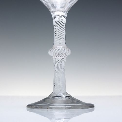 fig 2. An 18th-century clear glass wine glass featuring a multi-spiral opaque white twist stem with a central knop and a round foot.