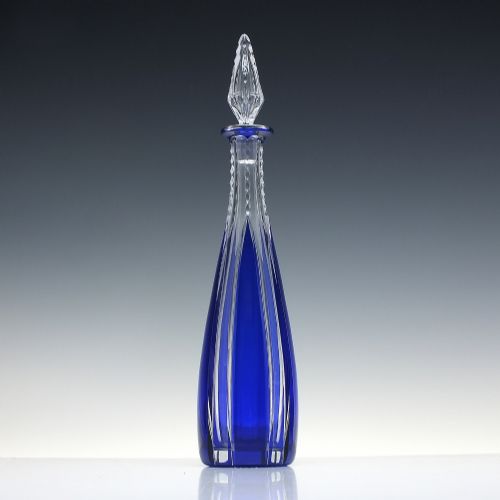 fig 1. A tall, slender cobalt blue cut-to-clear crystal spirit decanter featuring vertical faceted flutes and a pointed, clear faceted stopper.