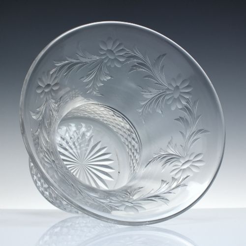 fig 1. A clear cut crystal vase featuring a flared upper rim with engraved floral details above a geometric diamond-cut lower body.