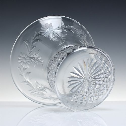 fig 2. A clear cut crystal vase featuring a flared upper rim with engraved floral details above a geometric diamond-cut lower body.