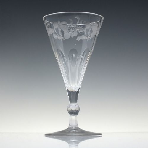 fig 1. A clear 19th-century Victorian glass goblet with wheel-engraved floral motifs around the upper rim and facet cutting on the lower bowl and knopped stem.