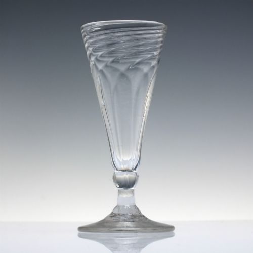 fig 1. An eighteenth-century clear glass ale goblet featuring spiral wrythen moulding on a conical bowl supported by a knopped stem and circular foot.