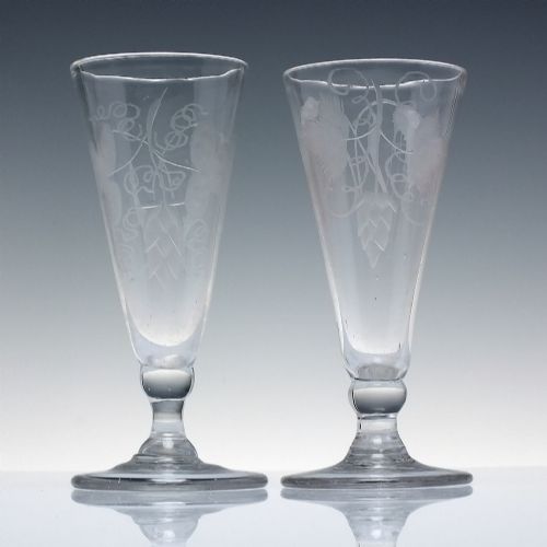fig 1. Pair of clear Georgian lead glass ale flutes featuring wheel-engraved barley and hops decoration on knopped stems.