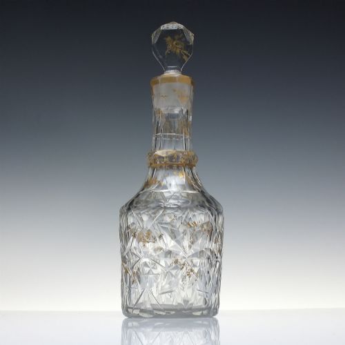 fig 1. A clear cut glass decanter with gilded lettering on the shoulder, a diamond facetted body, and a facetted glass stopper.