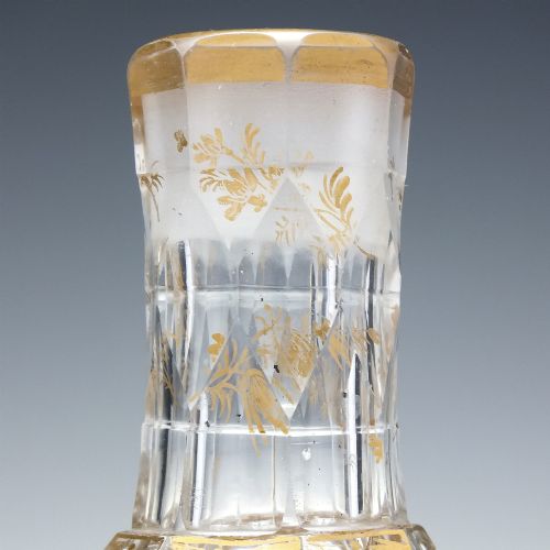 fig 3. A clear cut glass decanter with gilded lettering on the shoulder, a diamond facetted body, and a facetted glass stopper.