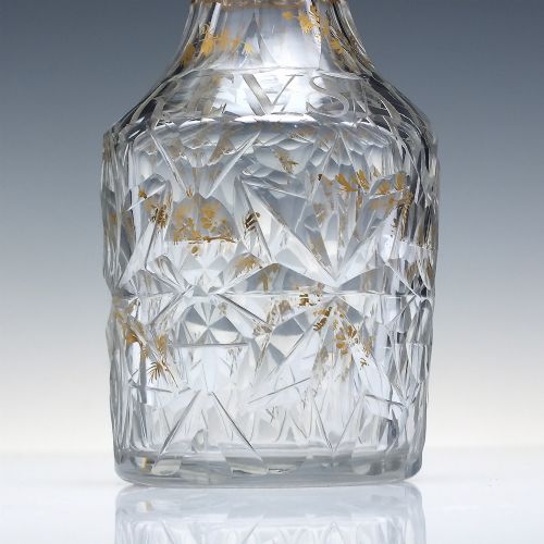 fig 5. A clear cut glass decanter with gilded lettering on the shoulder, a diamond facetted body, and a facetted glass stopper.