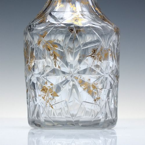 fig 6. A clear cut glass decanter with gilded lettering on the shoulder, a diamond facetted body, and a facetted glass stopper.