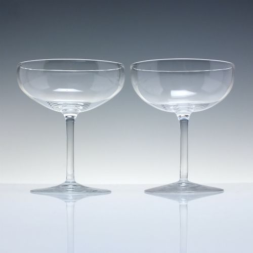 fig 1. A set of six clear Edwardian crystal champagne coupes with wide saucer bowls and slender stems arranged in a line.