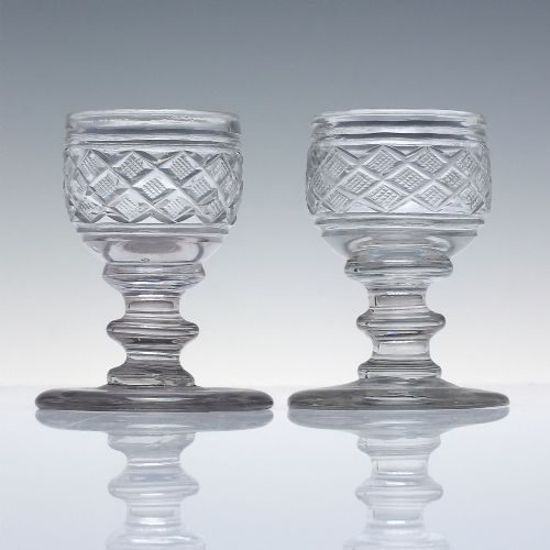 fig 1. A pair of early 19th-century clear cut lead crystal dram glasses featuring diamond cutting and knopped stems.