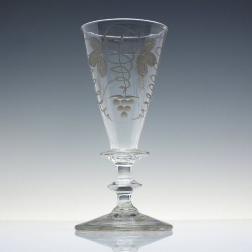 fig 2. A pair of clear hand-blown Georgian glass goblets featuring wheel-engraved motifs of hops and barley on conical bowls above knopped stems and conical bases.