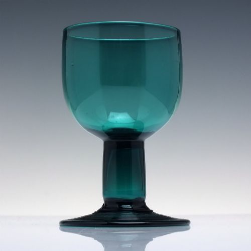 fig 1. An 18th-century emerald green hand-blown glass wine goblet featuring a rounded cup, thick cylindrical stem, and circular foot.