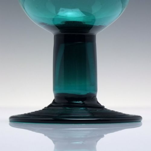 fig 2. An 18th-century emerald green hand-blown glass wine goblet featuring a rounded cup, thick cylindrical stem, and circular foot.