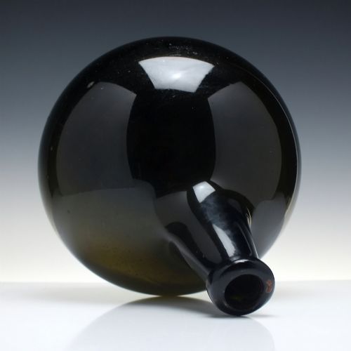 fig 2. A large, dark green hand-blown antique glass wine bottle with a bulbous body and tapered neck.