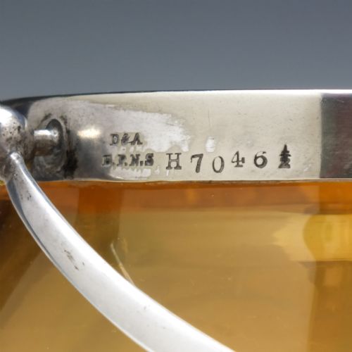 fig 5. An Art Nouveau amber glass biscuit barrel featuring green peacock eye trailing decoration and a silver-plated metal rim, lid, and swing handle.