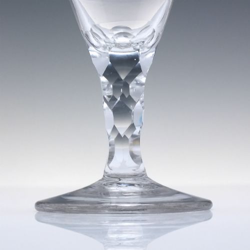 fig 2. An 18th-century clear lead crystal dram glass with a rounded bowl and a diamond facet-cut stem resting on a circular base.