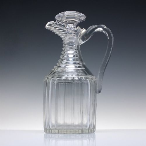 fig 1. A clear Georgian Regency cut glass claret jug with a step-cut neck, panelled body, applied handle, and faceted stopper.