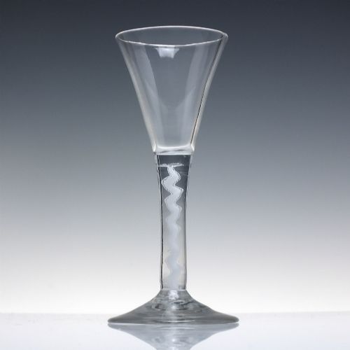 fig 1. An 18th-century clear lead glass wine glass featuring a flared trumpet bowl, a central white opaque twist stem, and a circular conical foot.