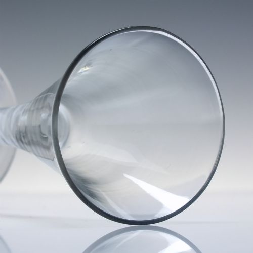 fig 4. An 18th-century clear lead glass wine glass featuring a flared trumpet bowl, a central white opaque twist stem, and a circular conical foot.
