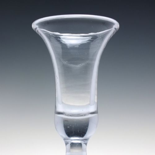 fig 2. An 18th-century clear glass firing glass featuring a flared trumpet rim, short stem element, and a heavy, thick round foot.