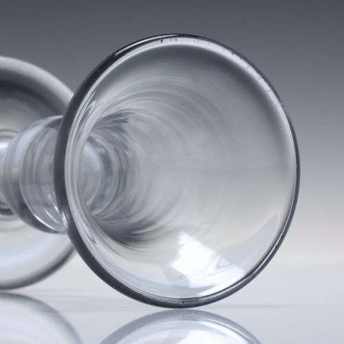fig 3. An 18th-century clear glass firing glass featuring a flared trumpet rim, short stem element, and a heavy, thick round foot.
