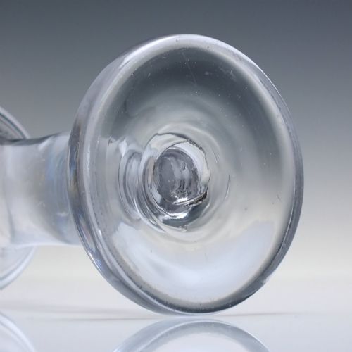 fig 4. An 18th-century clear glass firing glass featuring a flared trumpet rim, short stem element, and a heavy, thick round foot.