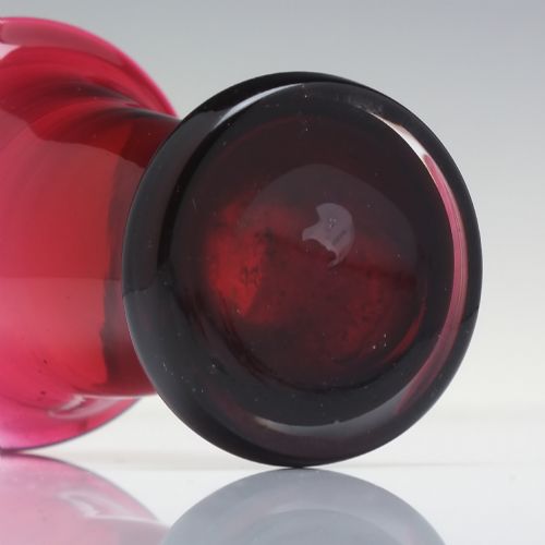 fig 3. A small Victorian ruby glass dram tumbler with a flared lip and heavy thick base against a plain background.